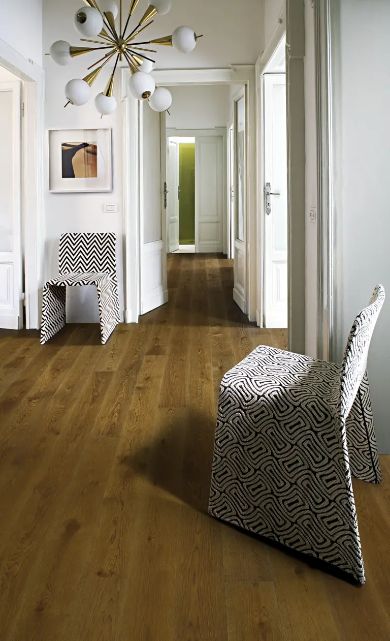 Oak Nouveau. A modern hallway with warm-toned oak flooring, geometric-patterned chairs.