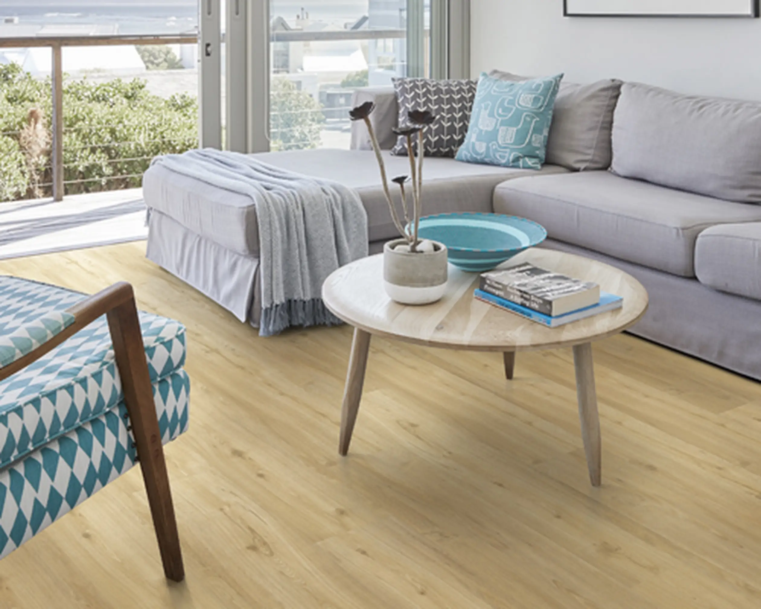 Bright living room with light wood flooring, a grey sofa, and ocean views.