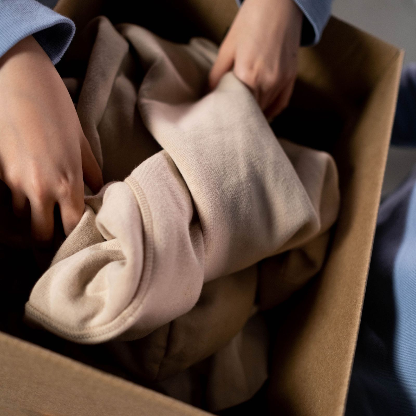 hands putting a garment in cardboard box