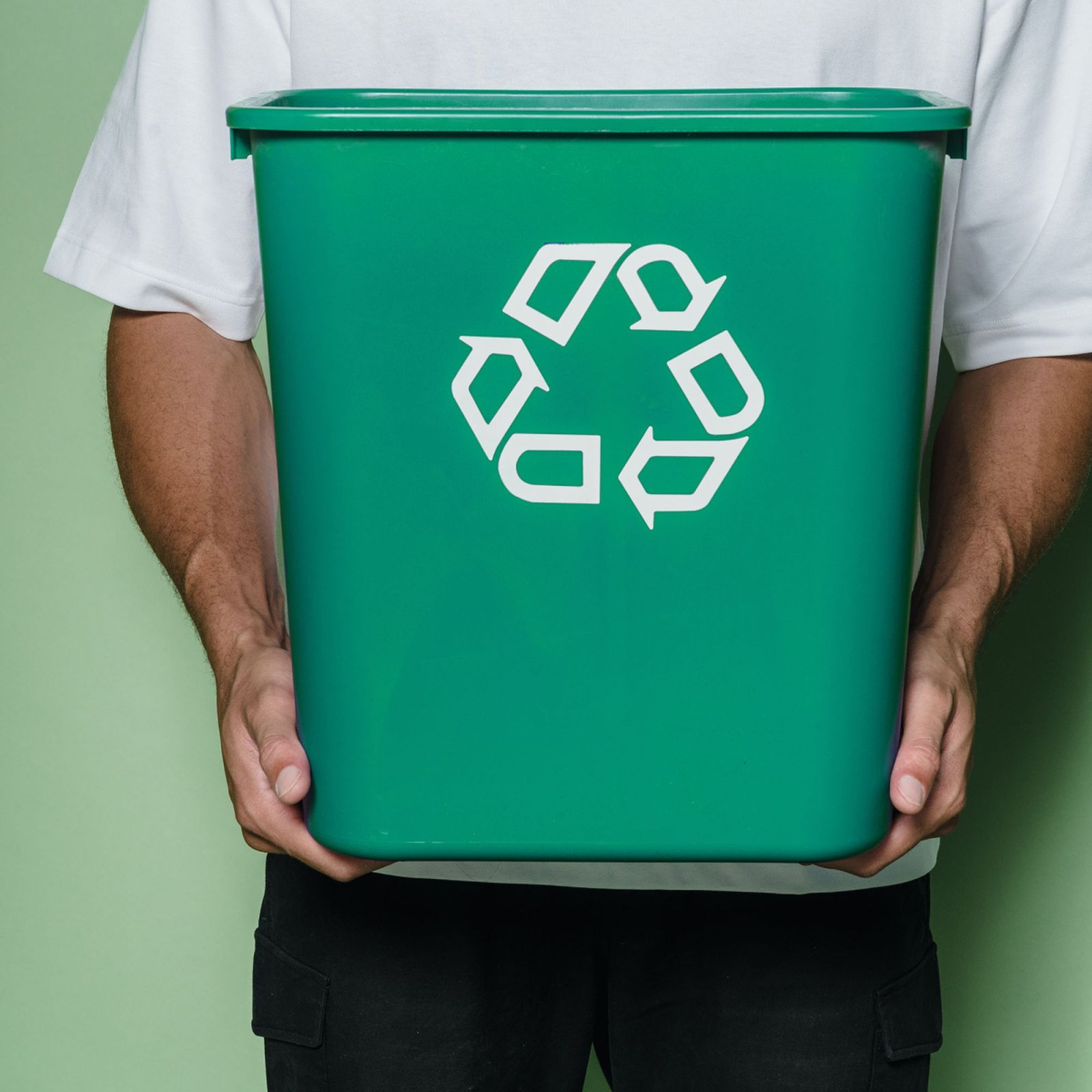 someone holding a green recycling bin