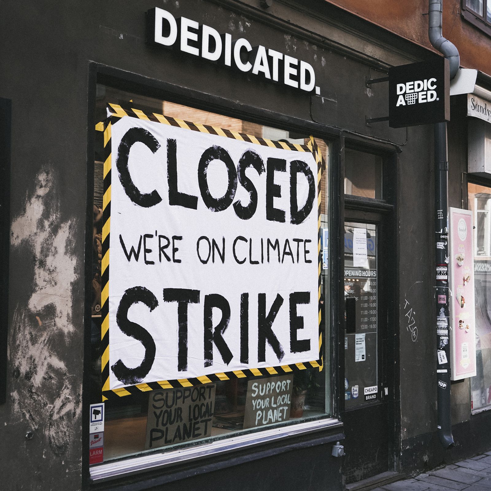 Storefront with a large sign reading "Closed We're on Climate Strike." Smaller signs in window promote local planet support.