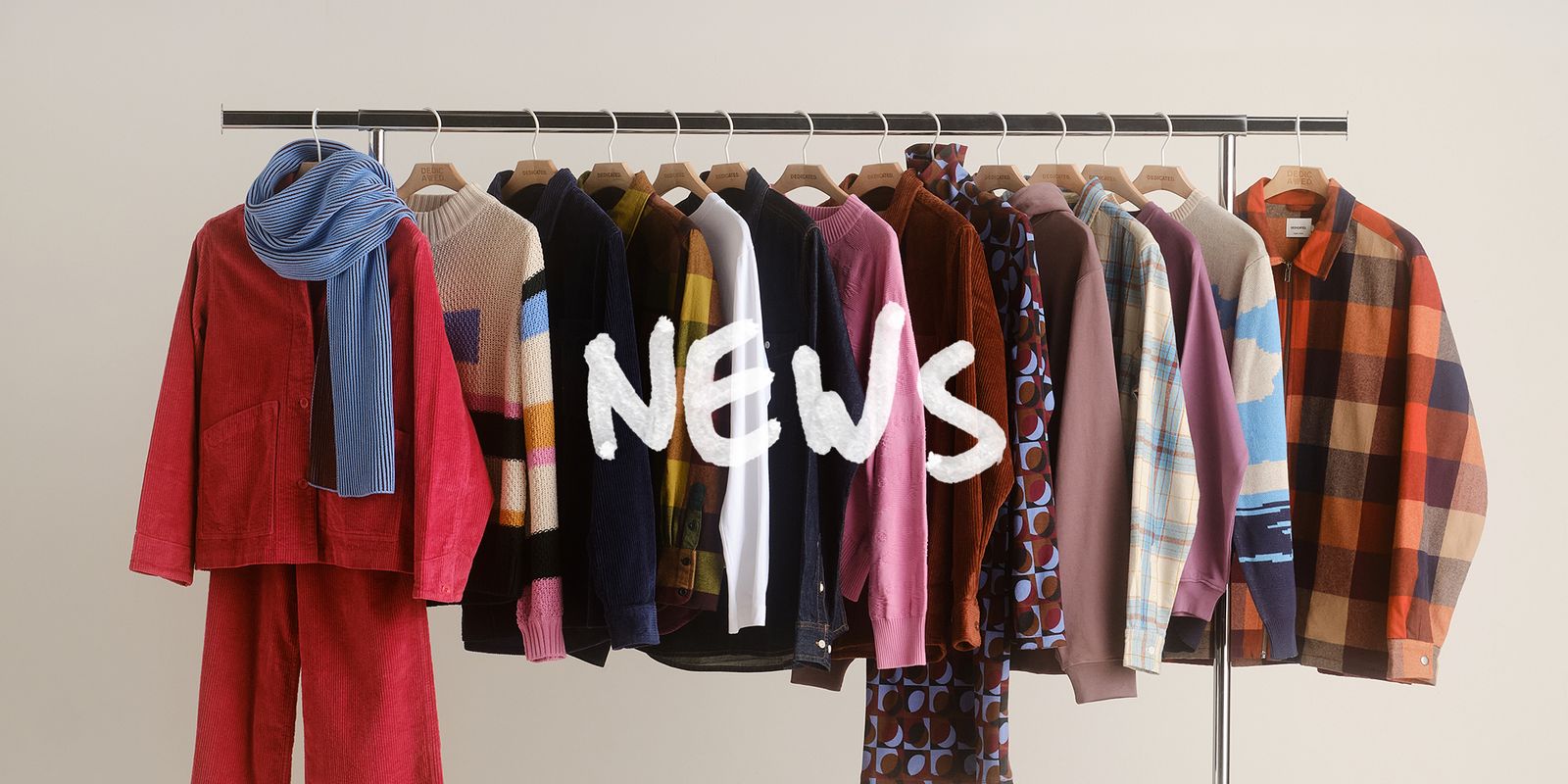 Clothing rack with colorful garments, including sweaters, jackets, and scarves. The word "NEWS" is overlayed in white.