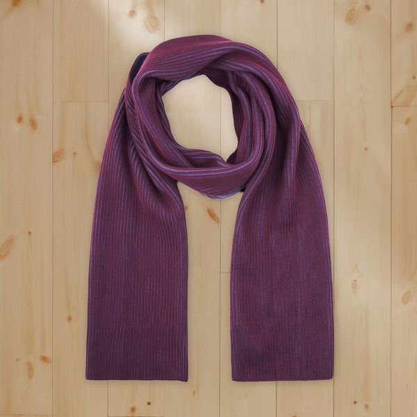 Ribbed purple and blue striped knit scarf looped at top with ends draped on a light wooden plank floor