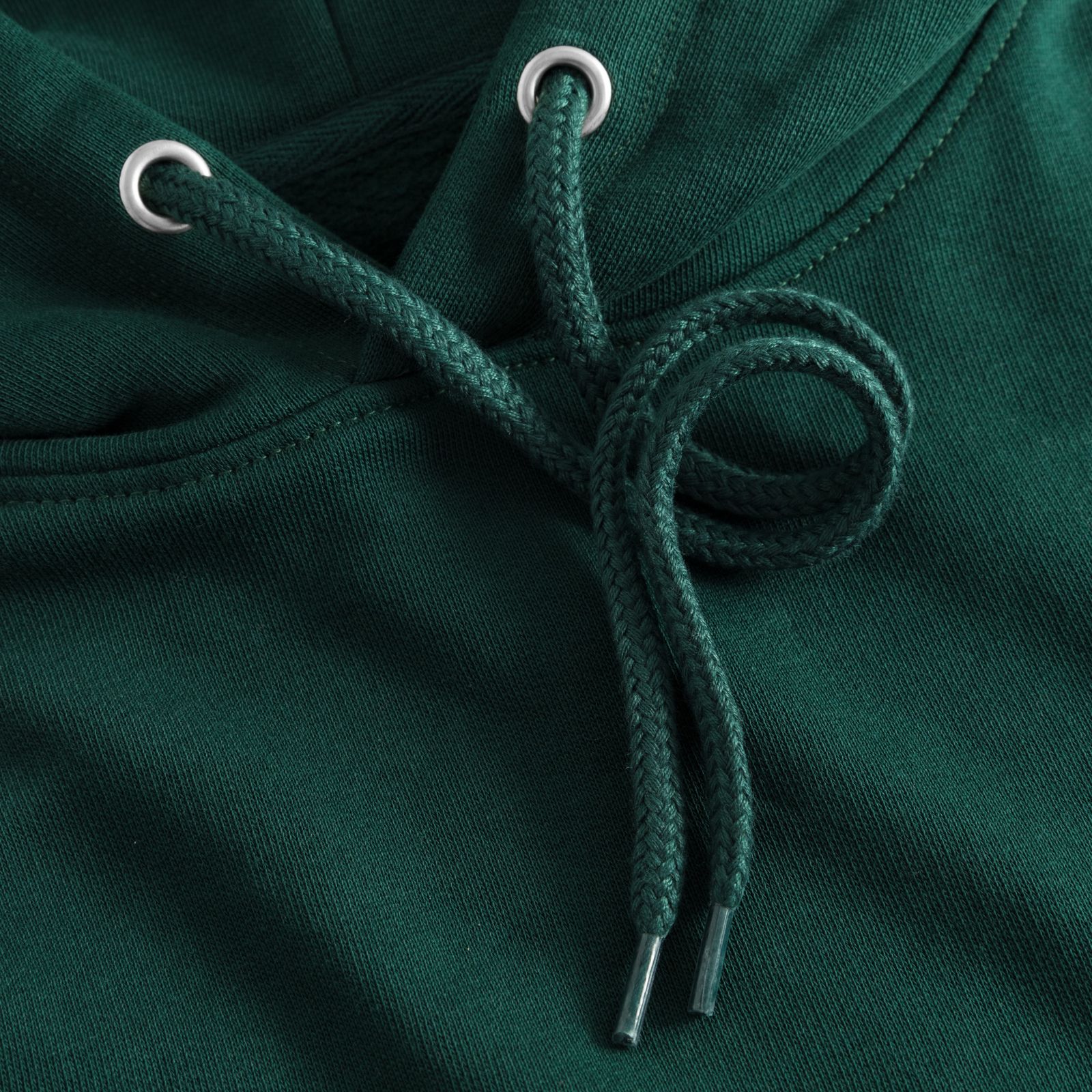 Close-up of a dark green hoodie with a drawstring tied in a loop, featuring metal eyelets and plastic aglets on the ends.