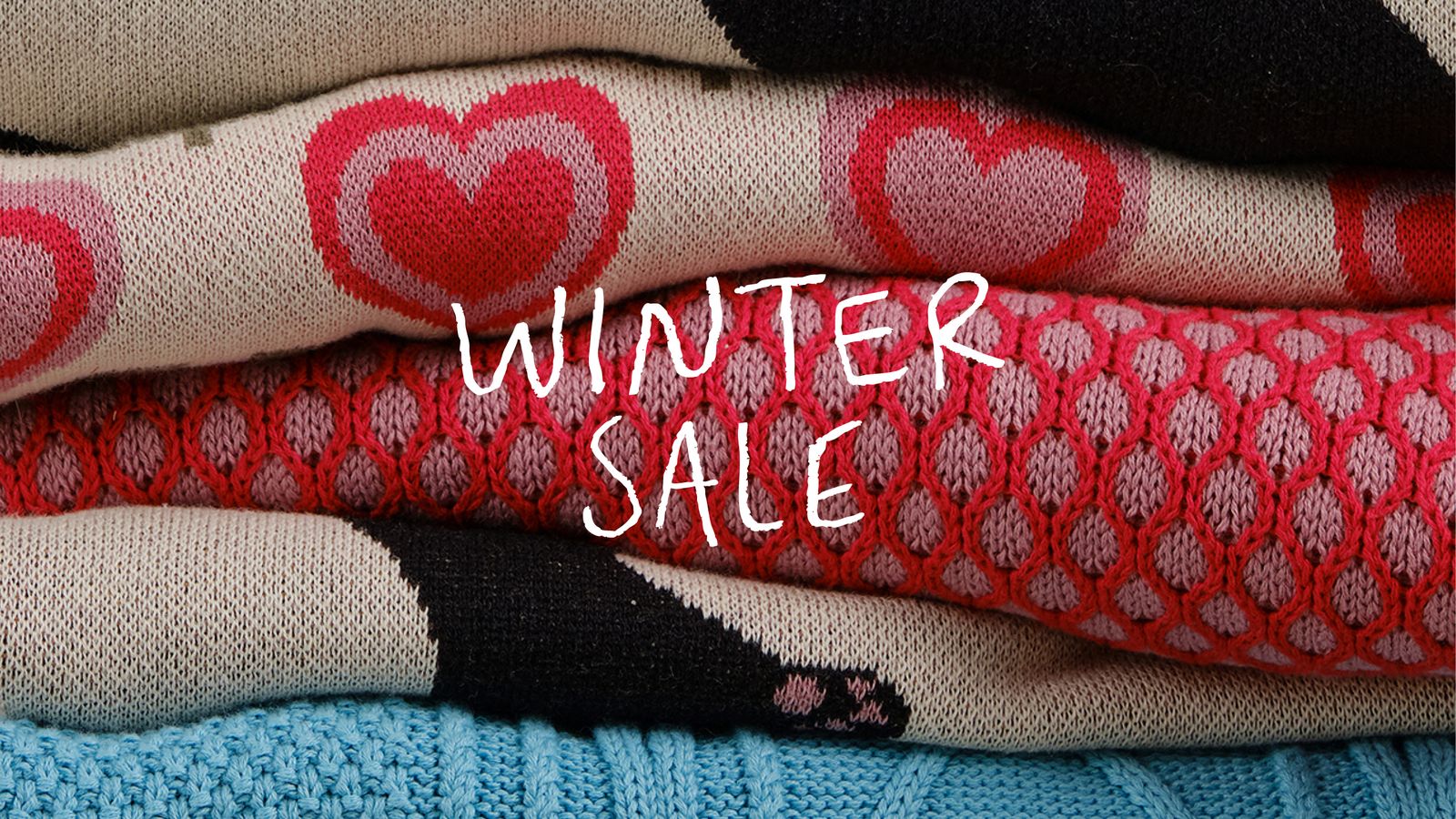 Stack of colorful winter sweaters with heart patterns, overlaid with the text "Winter Sale."