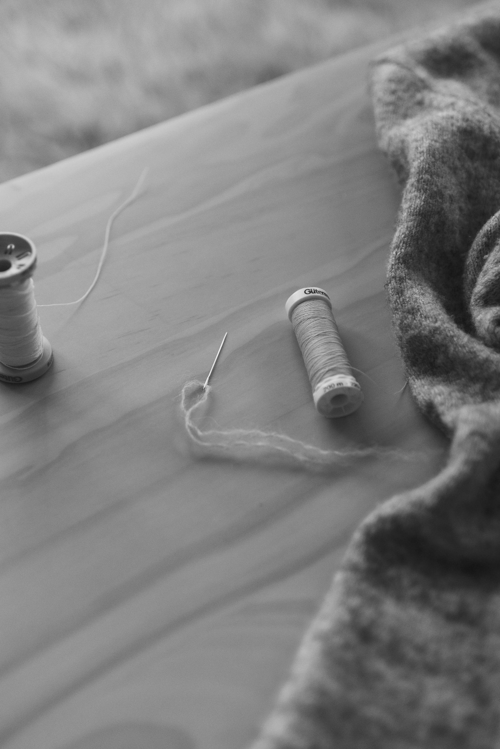 black and white sweater on a table with a little roll of thread