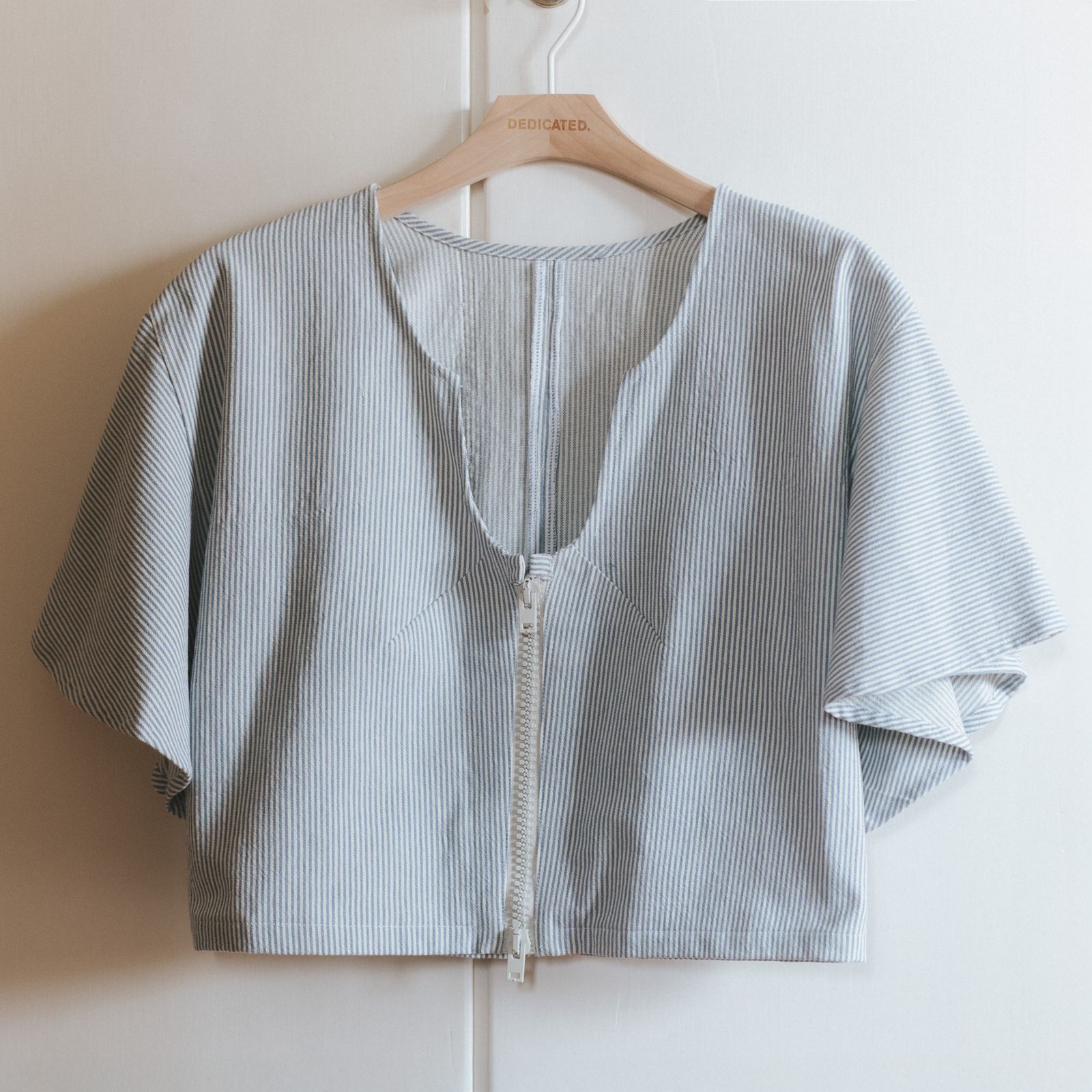 A top in striped white and blue hanging infront of a wardrobe