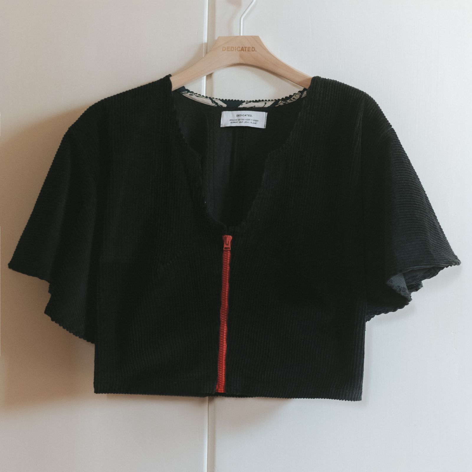 Blouse in black corduroy hanging infront of a wardrobe