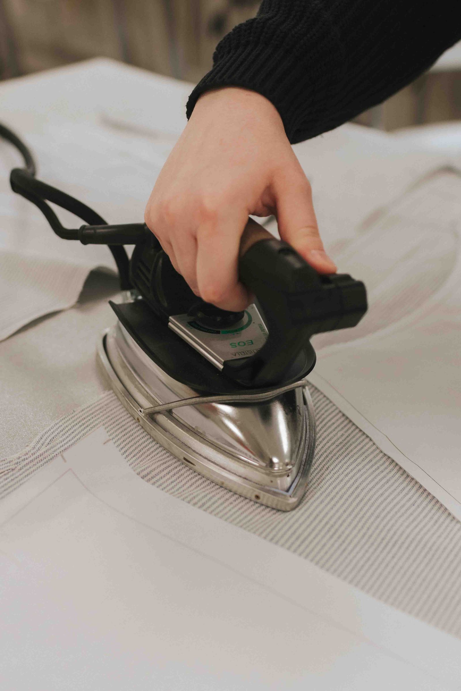 A upclose picture of a hand ironing garment