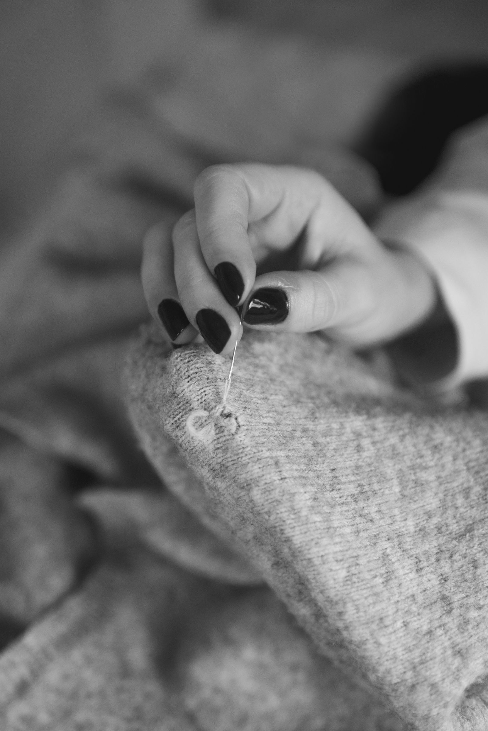 A hand fixing a whole in a sweater black and white