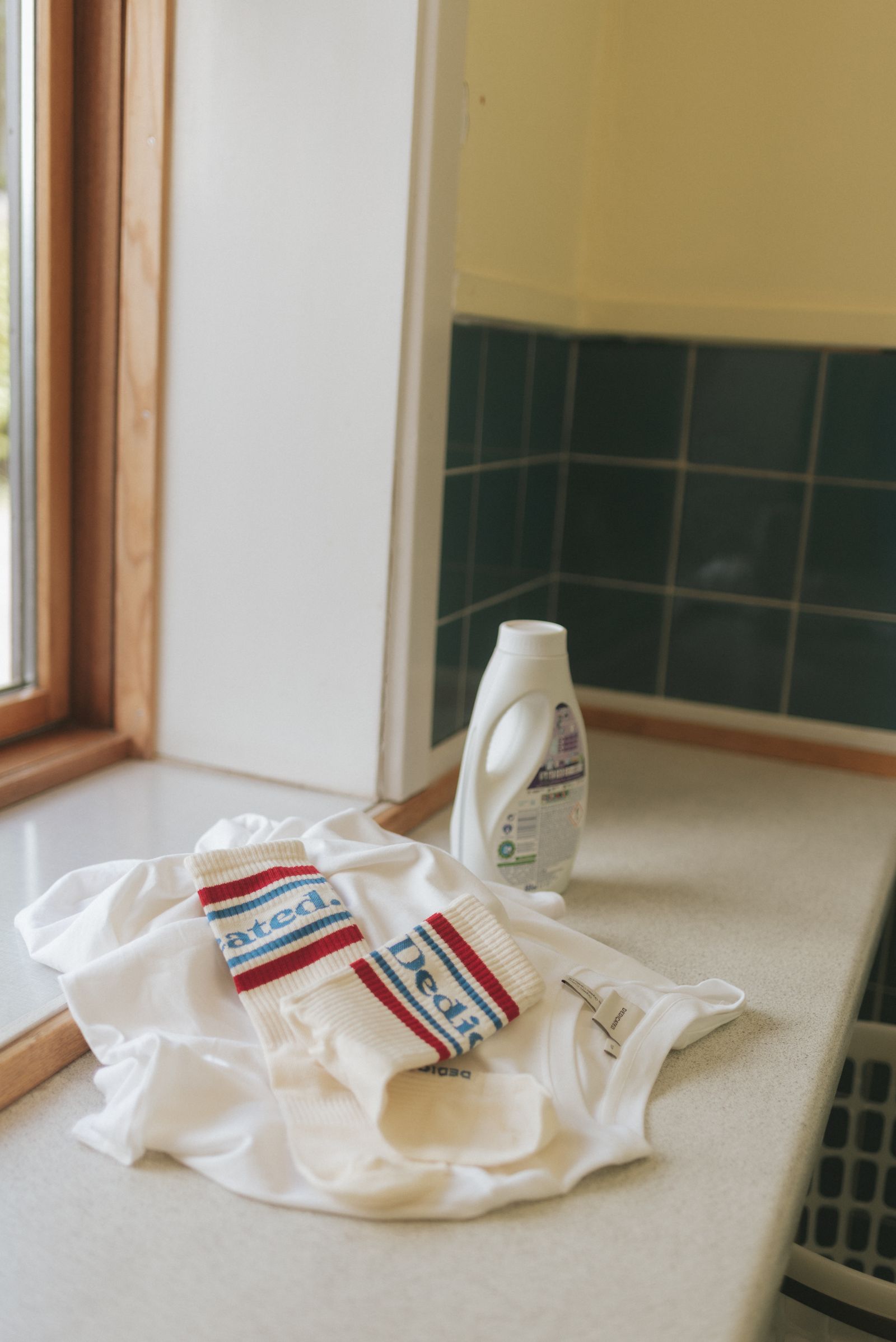dedicated tshirt and socks by a window with laundry detergent bottle
