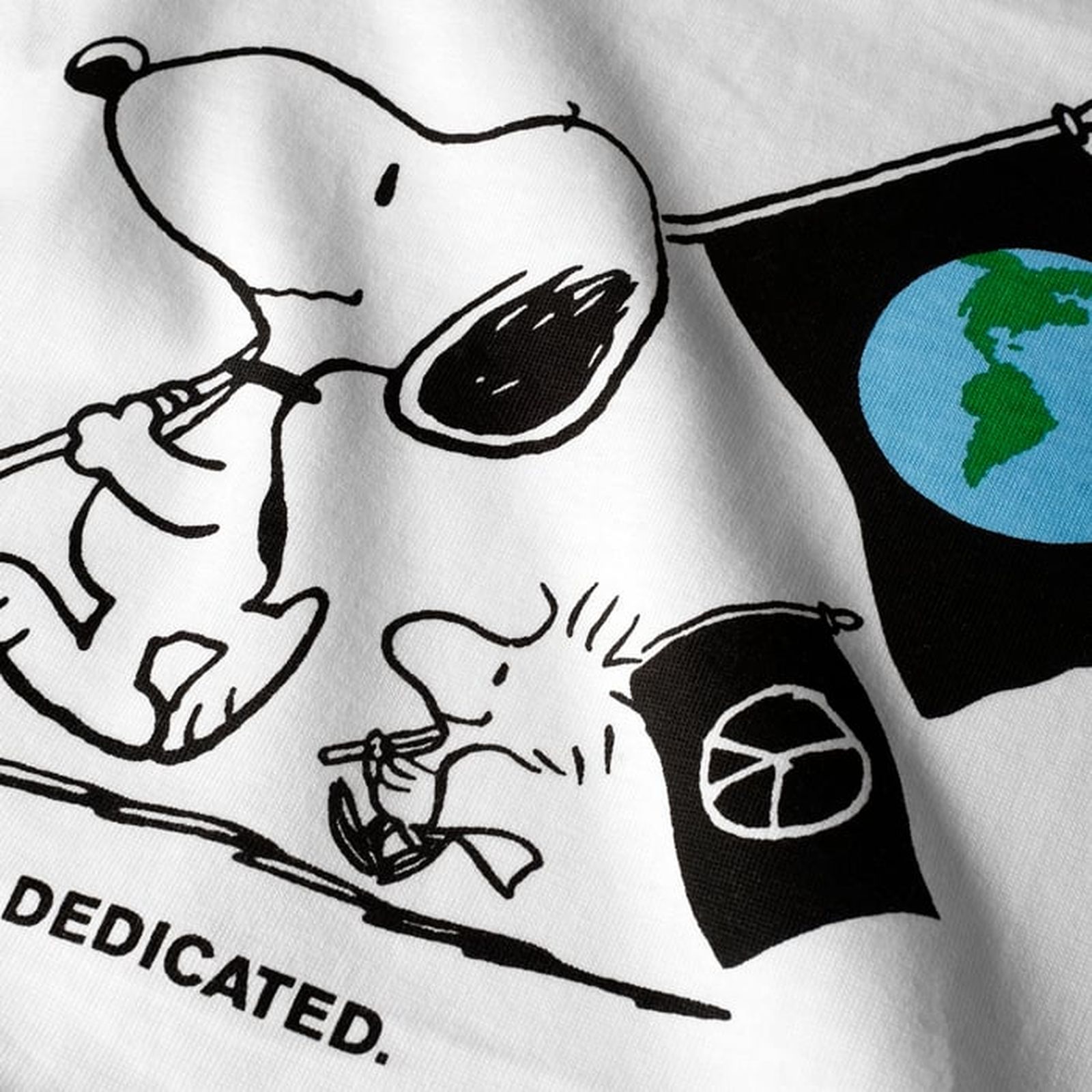 Illustration of Snoopy and Woodstock carrying flags; Snoopy's flag has a globe, Woodstock's has a peace symbol. Text: "DEDICATED."