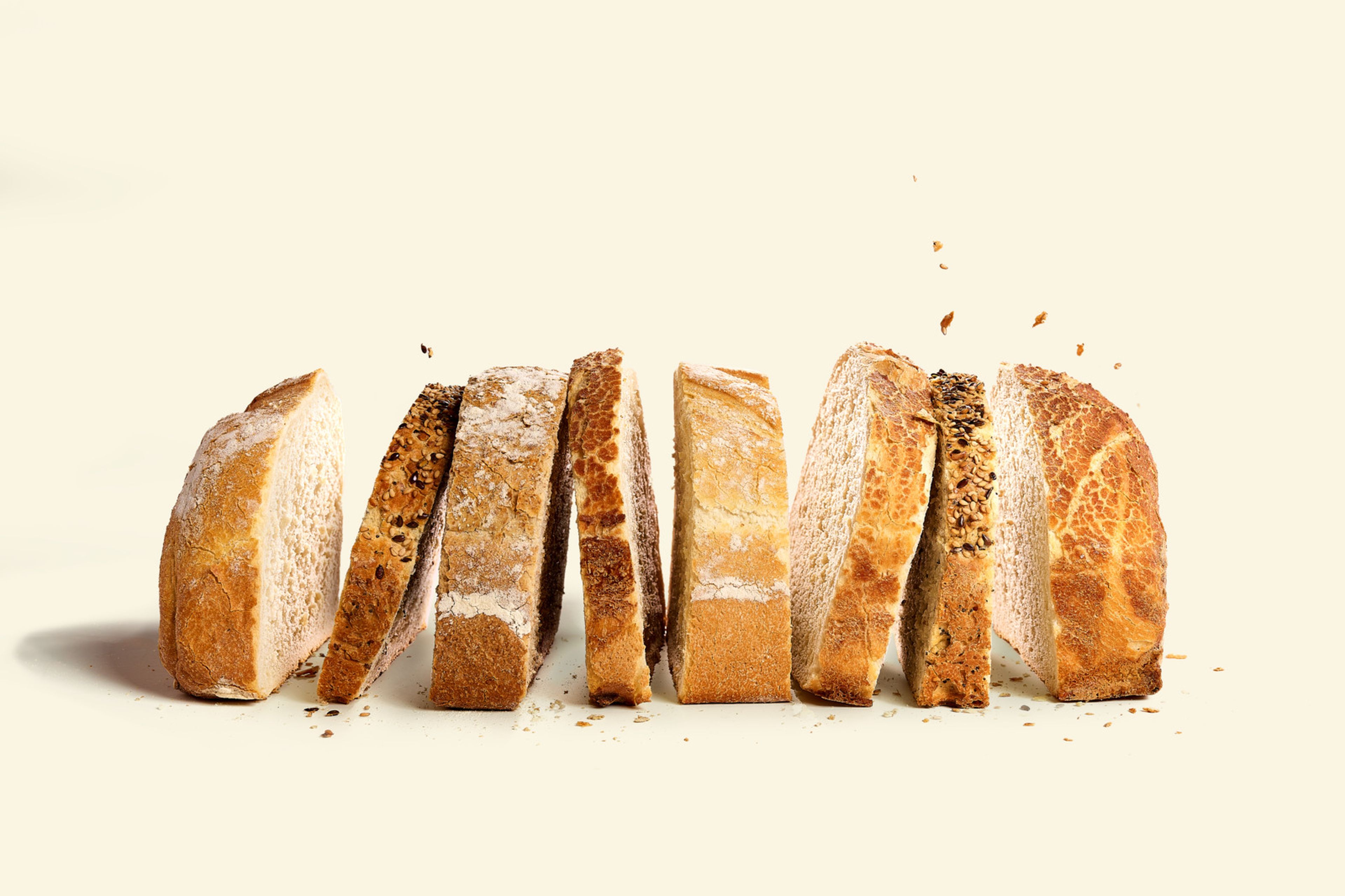 Pain Qubo tranché de chez Panos, présenté debout sur un fond clair. Les tranches montrent différentes croûtes et types de graines, avec un aspect artisanal et rustique.