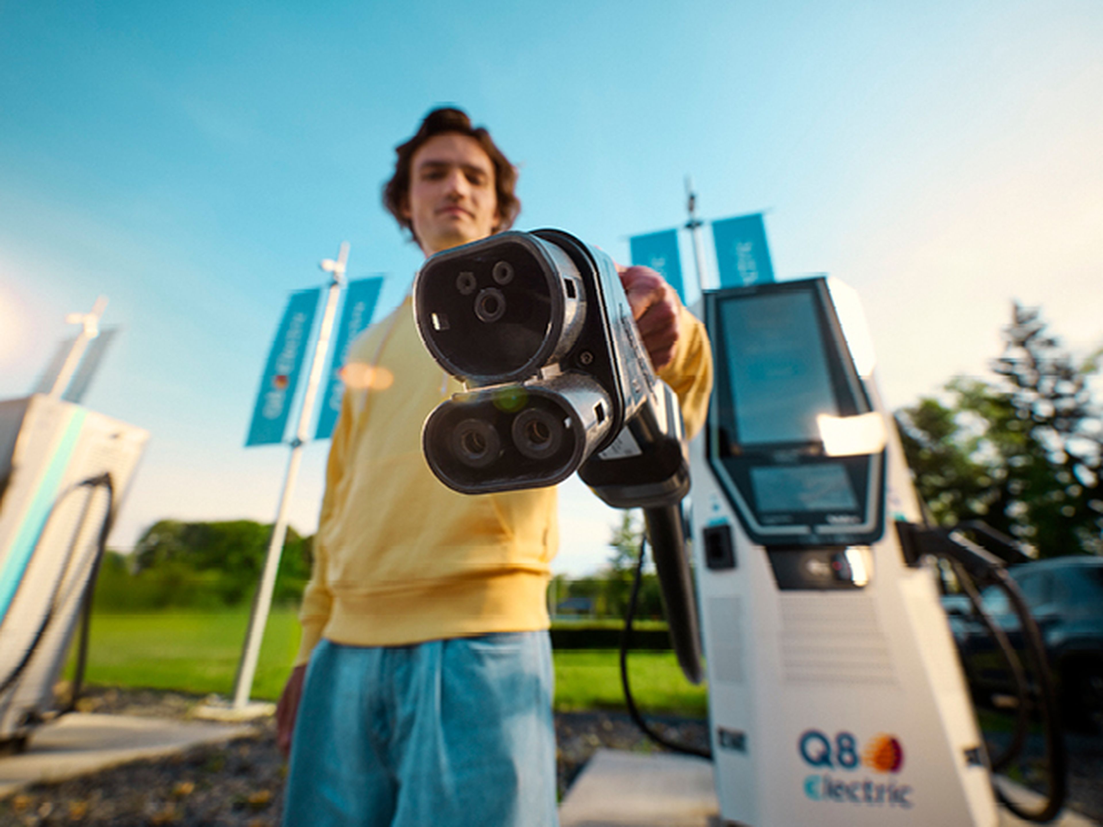 Homme montre une prise de recharge Q8 Electric à la caméra.​