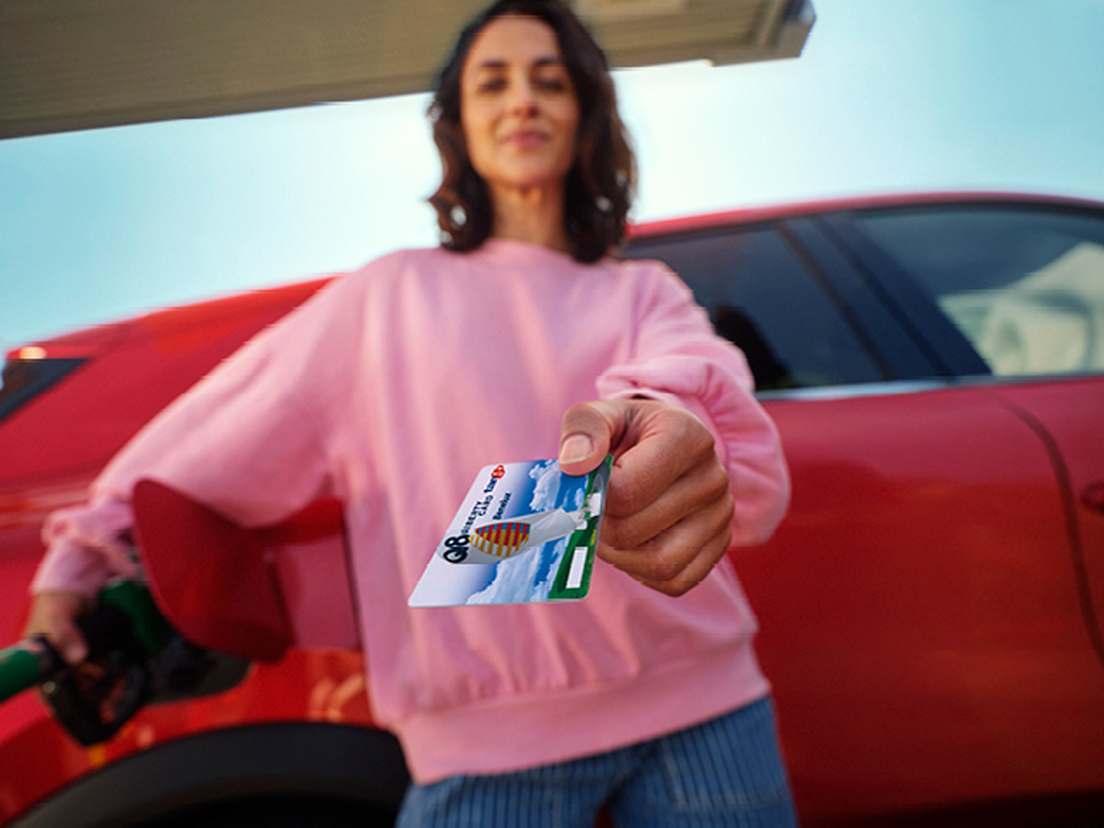 vrouw houdt een Q8 liberty tankkaart en is auto aan het tanken
