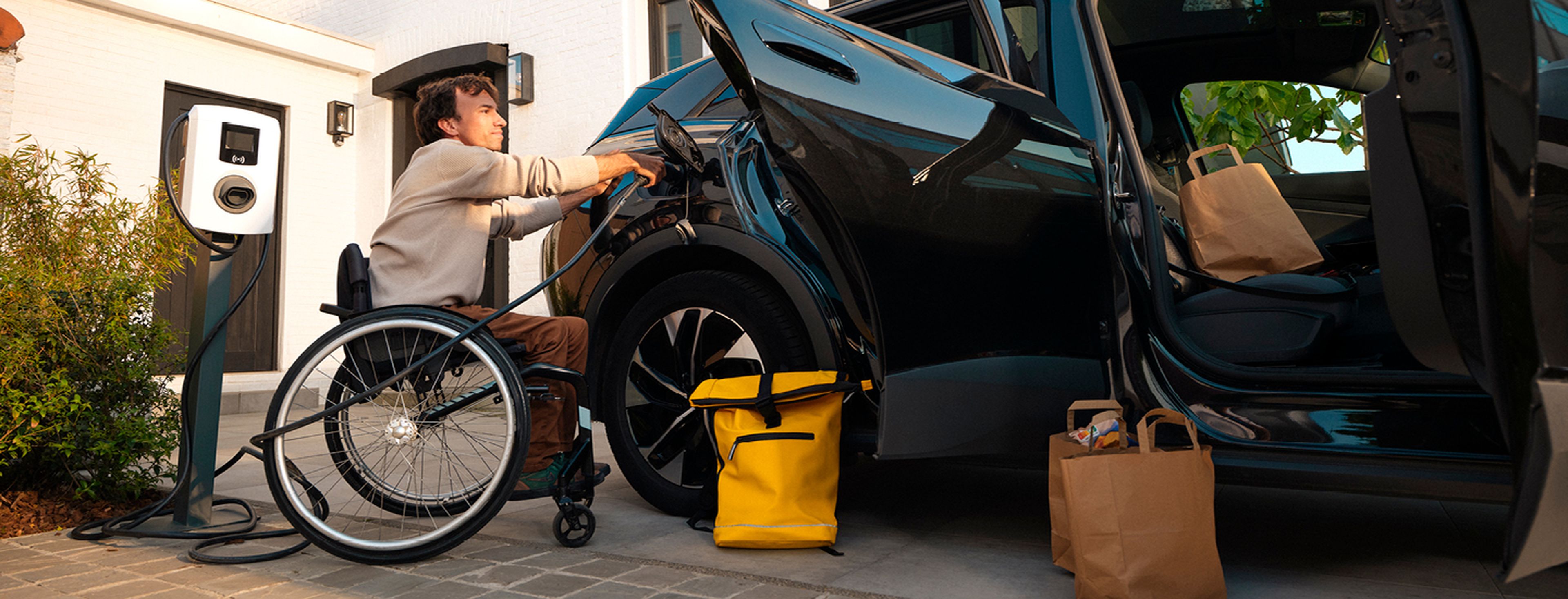 Man in a wheelchair charges electric car using a Q8 electric home charger.