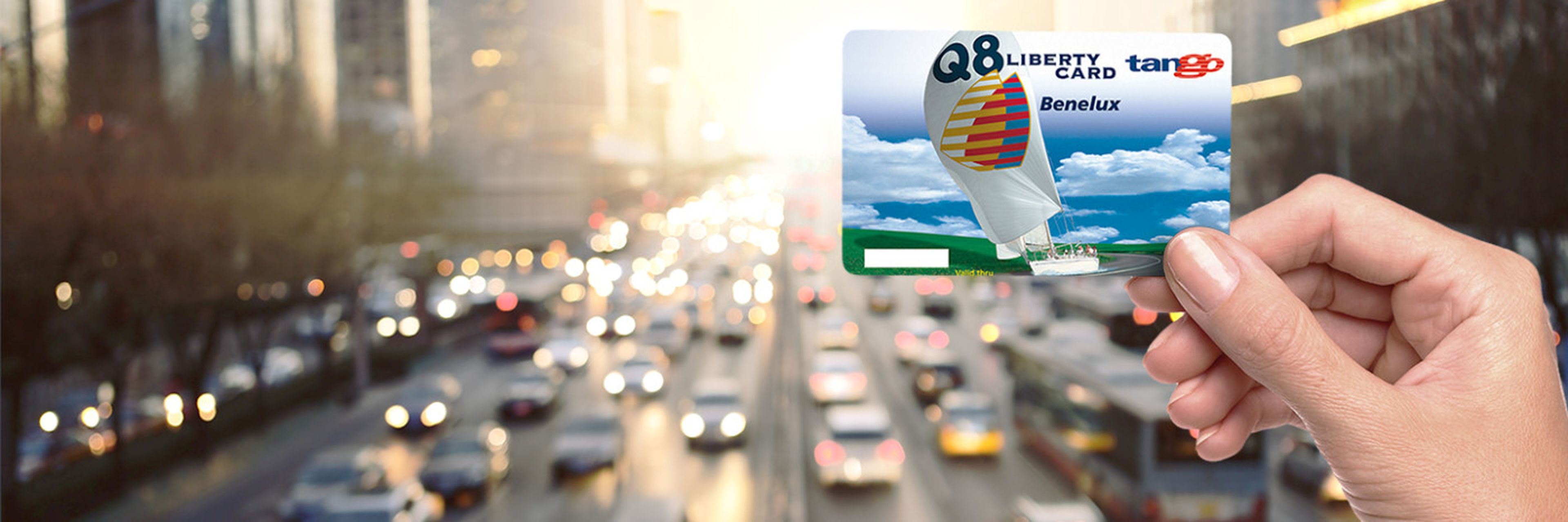 De Q8 Liberty Card wordt vastgehouden, met auto's op de achtergrond.