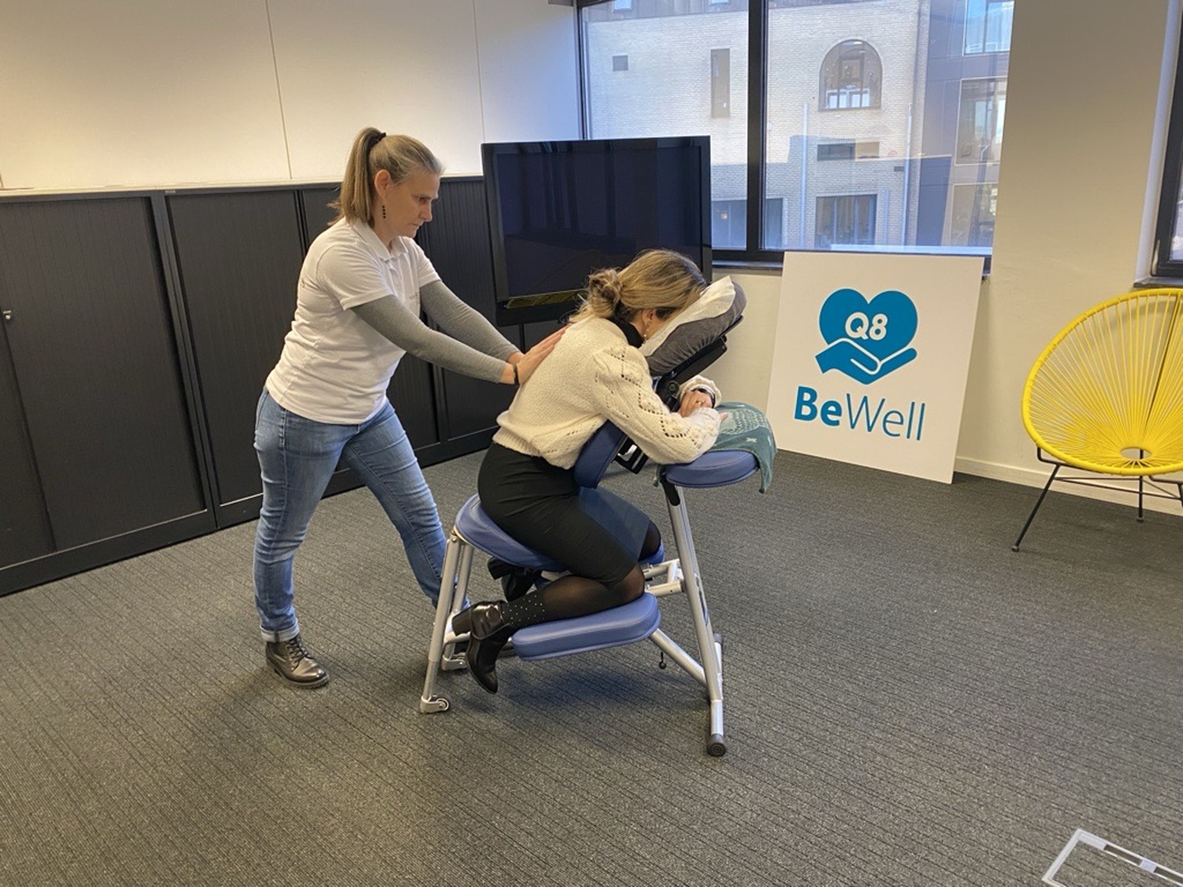A woman is giving a massage to a Q8 colleague.