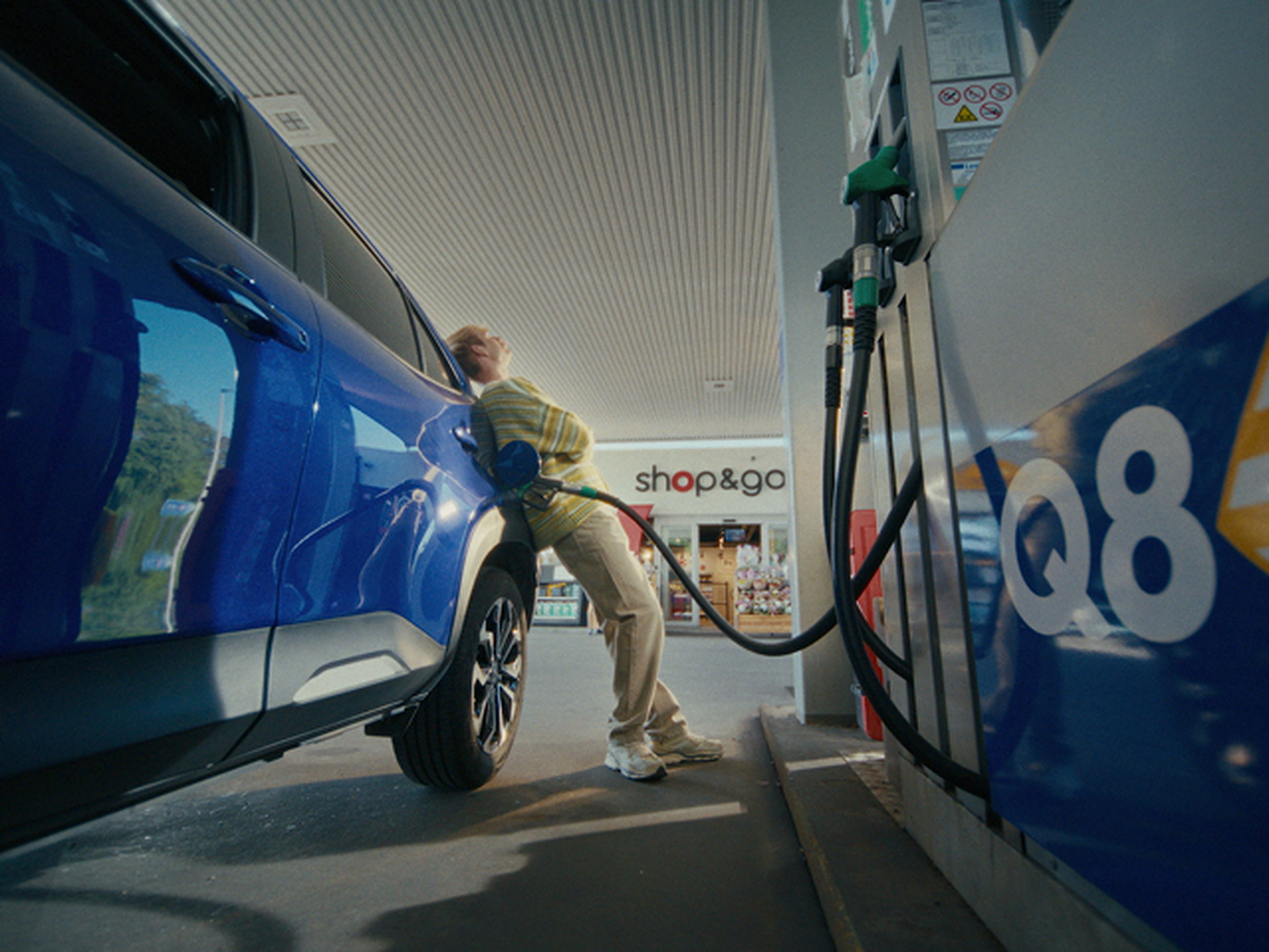Man leunt tegen auto tijdens tanken bij Q8.