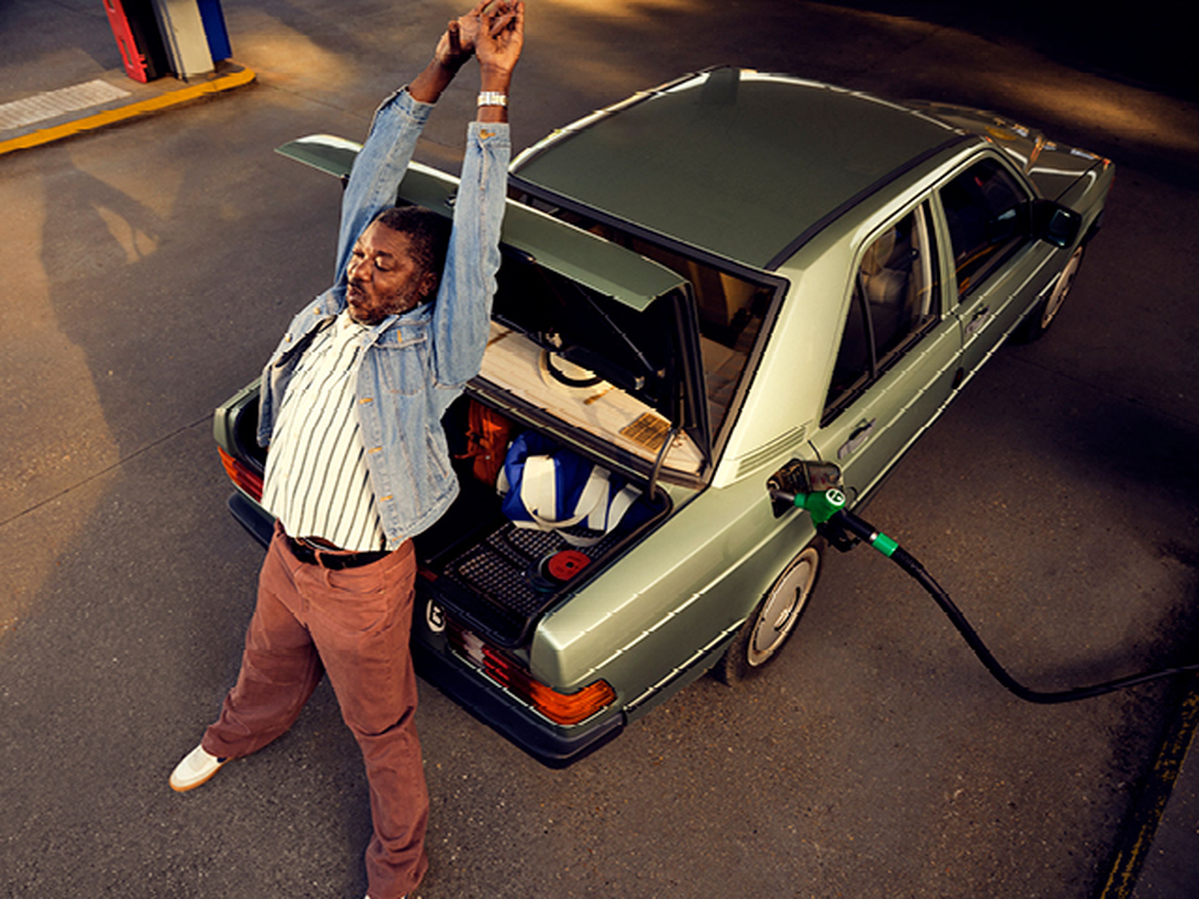 Man stretching while fueling his mercedes