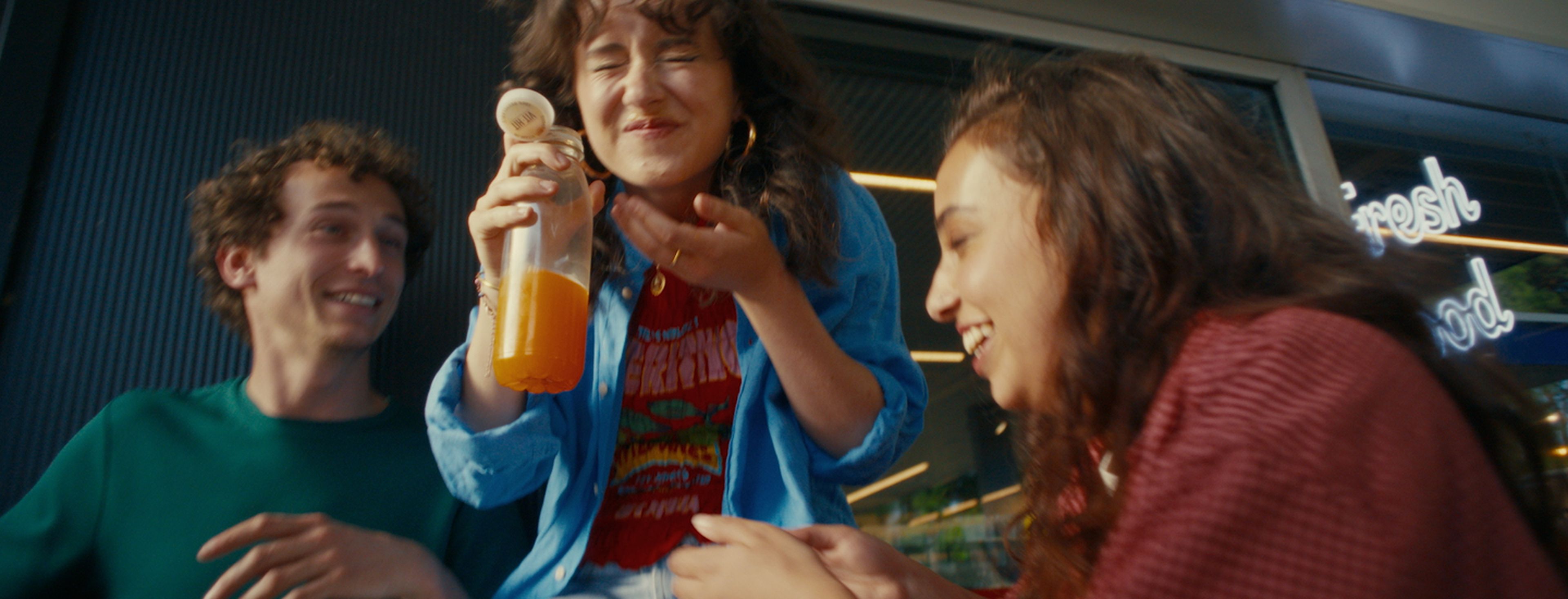 Een groep vrienden lachen en genieten van een drankje bij een Q8 Shop