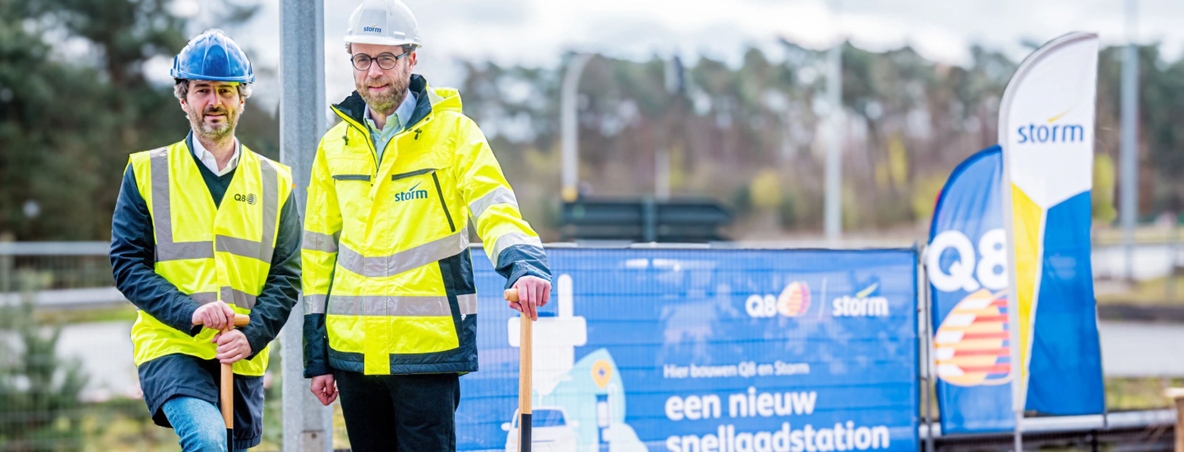 Vertegenwoordigers van Q8 en Storm staan op de bouwlocatie van een nieuw snellaadstation, als symbool voor hun samenwerking om de infrastructuur voor duurzame mobiliteit uit te breiden.
