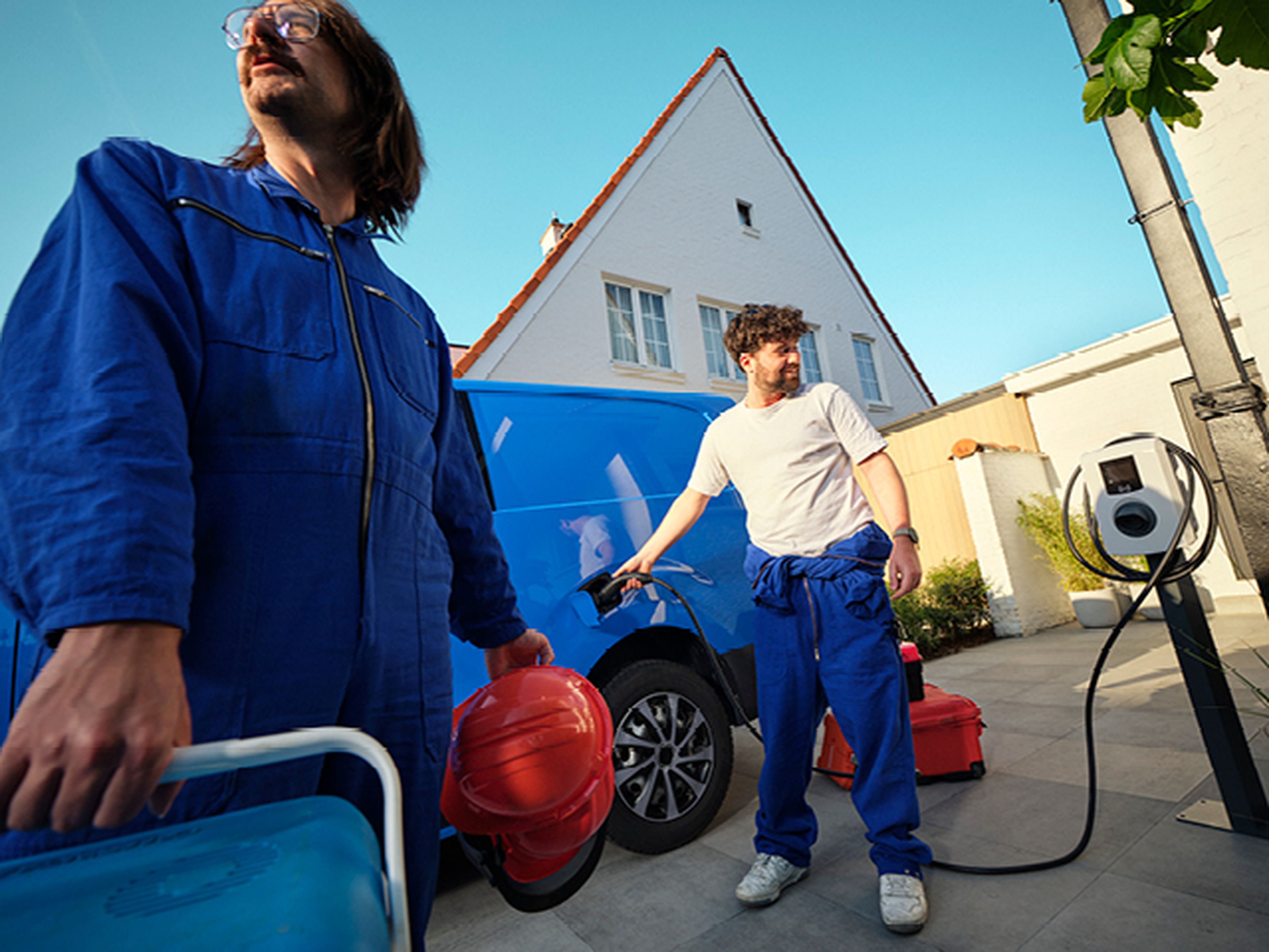 Mannen laden een blauw busje op met een Q8 thuislaadpaal