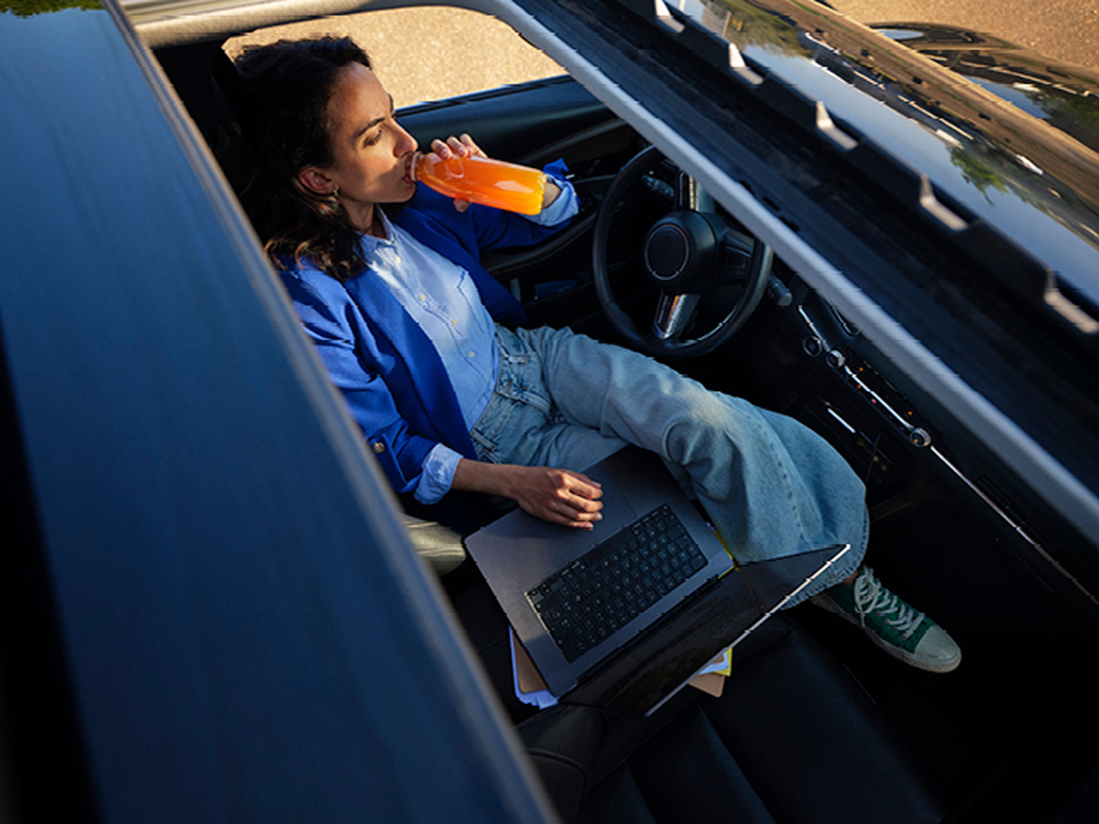 Femme travaille sur ordinateur portable en voiture chez Q8.​