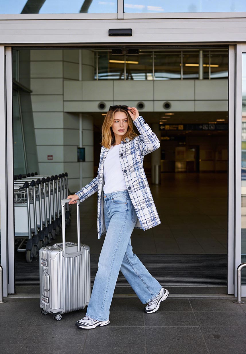 Frau am Flughafen mit Karoblazer und Denim