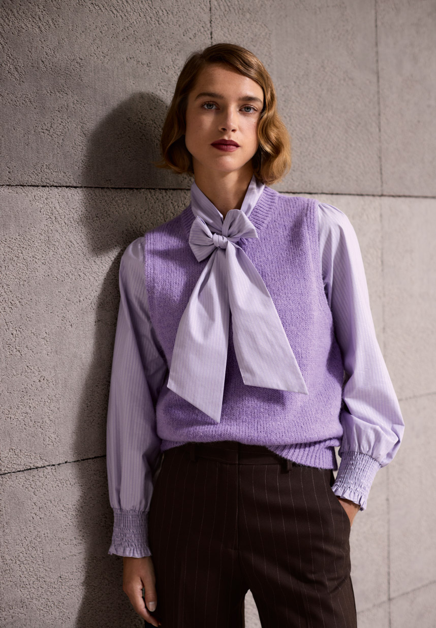 Frau mit lila Bluse und lila Pullunder