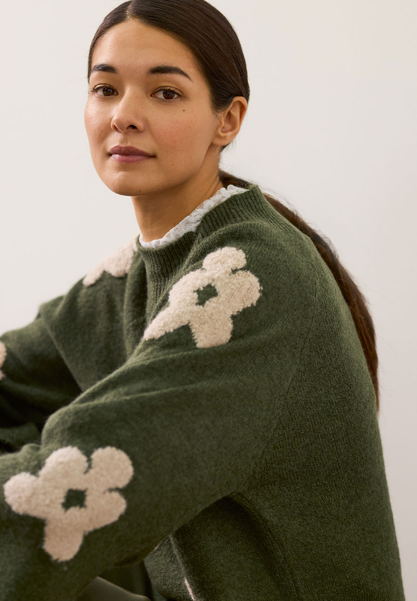 Frau mit grünem Pullover mit Blumen