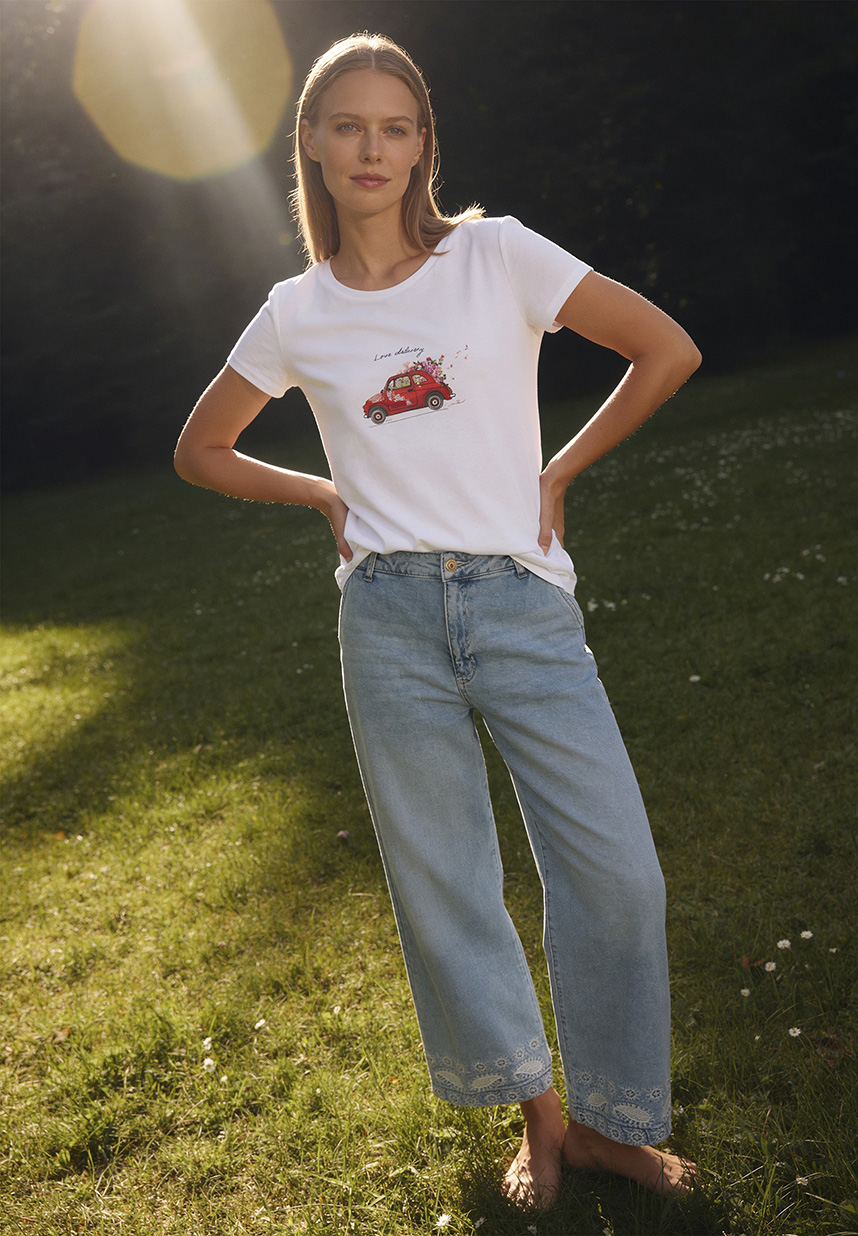 Model in Jeanshose und Shirt stehend in einer Wiese