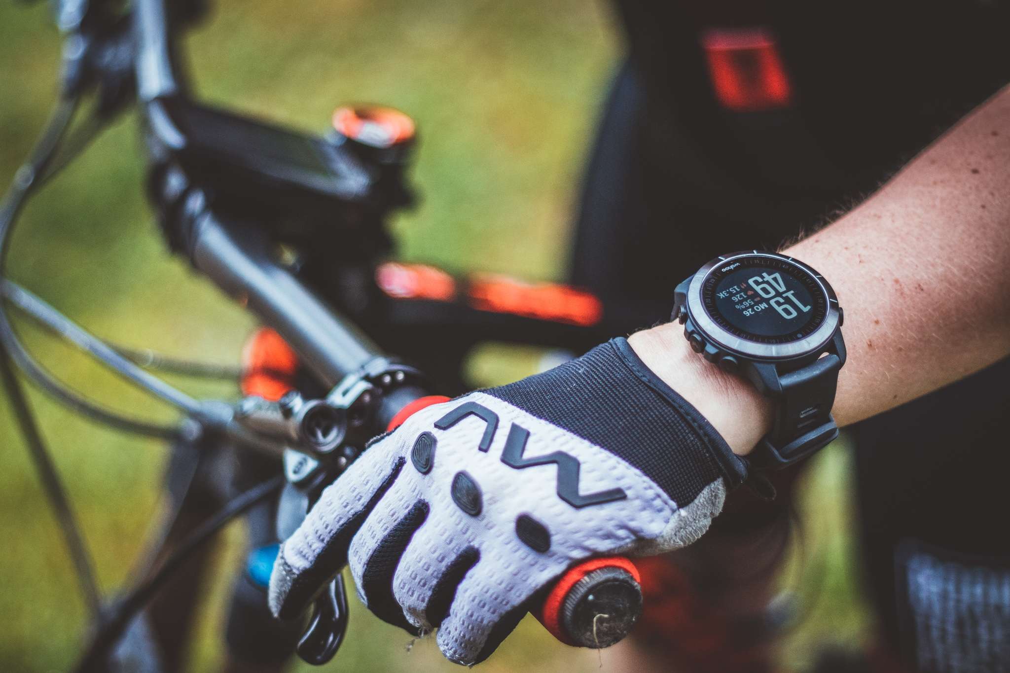 Hand mit Fahrradhandschuh am Lenker Am Arm ist eine Smartwatch zu sehen
