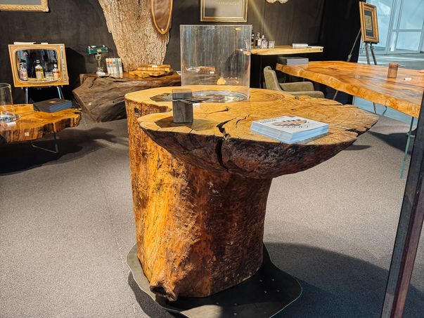 Standing table made from a whole ash trunk with natural live edge and integrated fire section