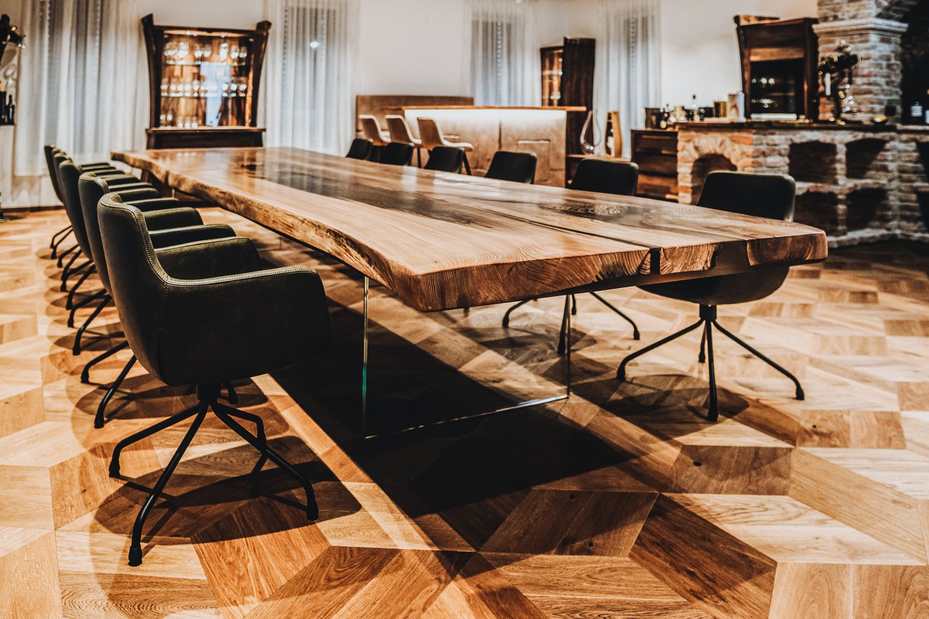 Gran mesa de madera natural de olmo con patas de vidrio resistentes y canto vivo característico