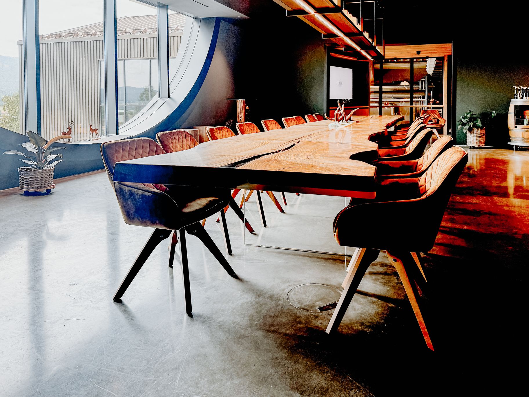 Mesa de madera maciza de Stammdesign hecha de un solo tronco de fresno, con borde natural, patas de vidrio y presencia impresionante en un loft