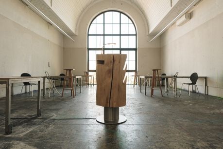 Escritorio de madera maciza natural en el centro de una sala con gran ventana de Stammdesign
