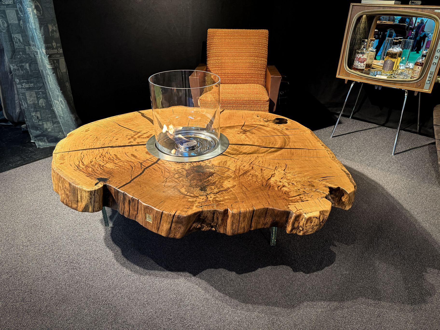 Table basse en chêne avec bord naturel provenant d’une tranche de tronc, placée à côté d’un fauteuil moderne