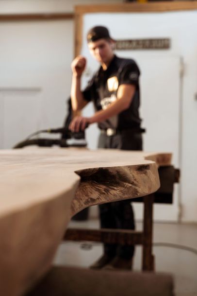 Baumstammtisch wird in der Stammdesign Manufaktur von Hand geschliffen – Herstellung eines modernen Massivholz Designmöbels