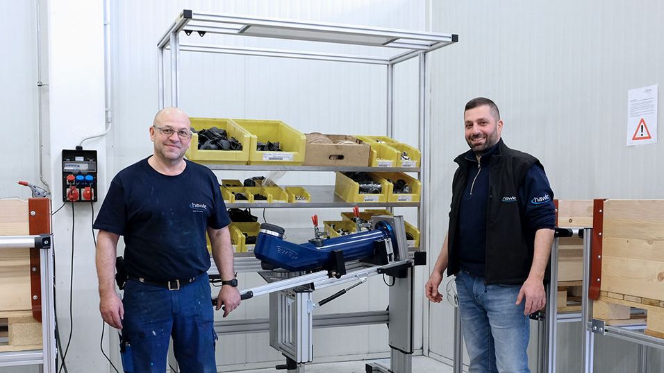 Two employees stand in front of an assembly workstation with a swivelling device