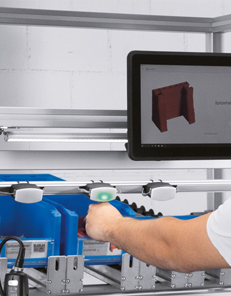 Employee picks up a component which is indicated by the pick by light sensor
