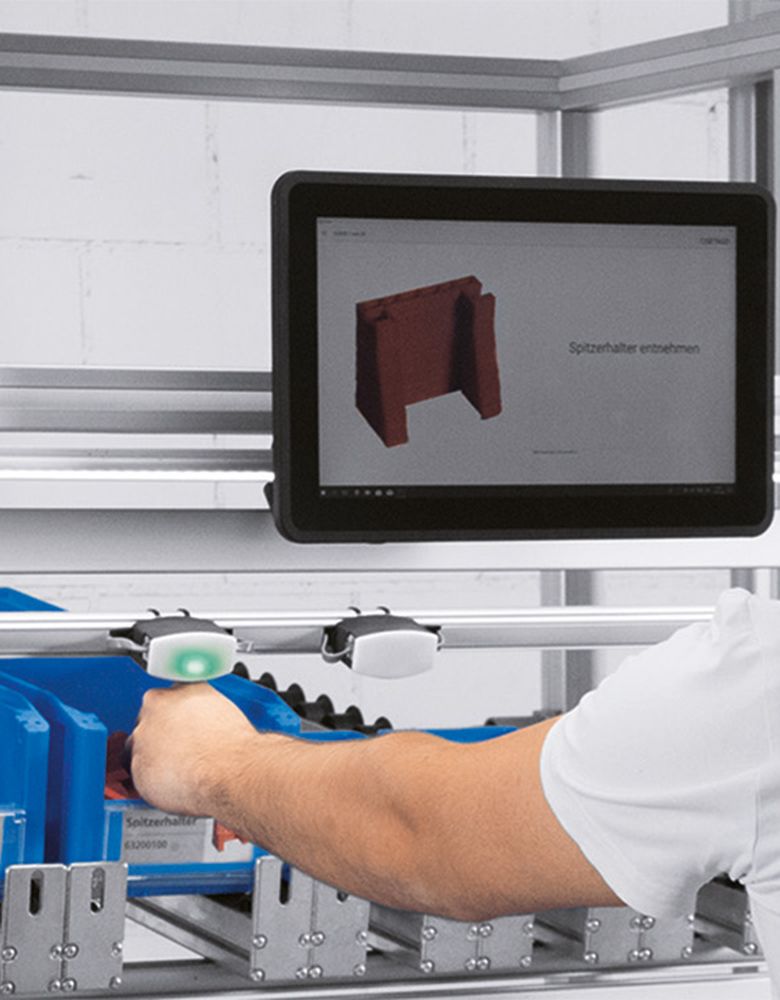 Employee picks up a component which is indicated by the pick by light sensor
