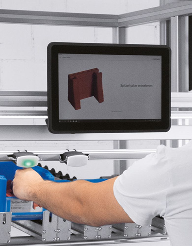 Employee picks up a component which is indicated by the pick by light sensor