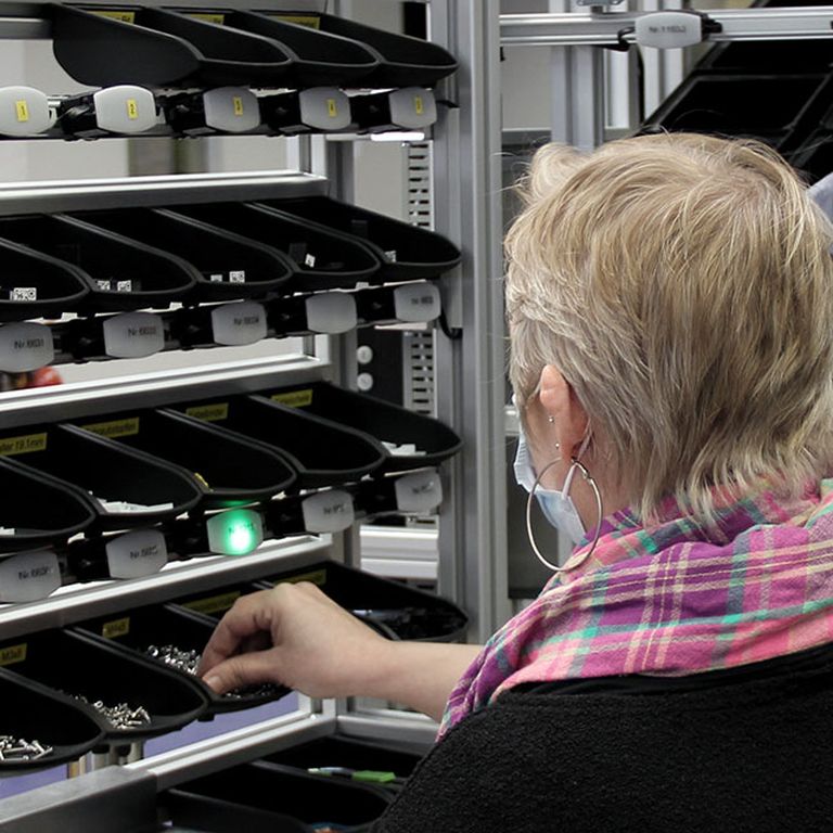 Employee picks a component out of a container