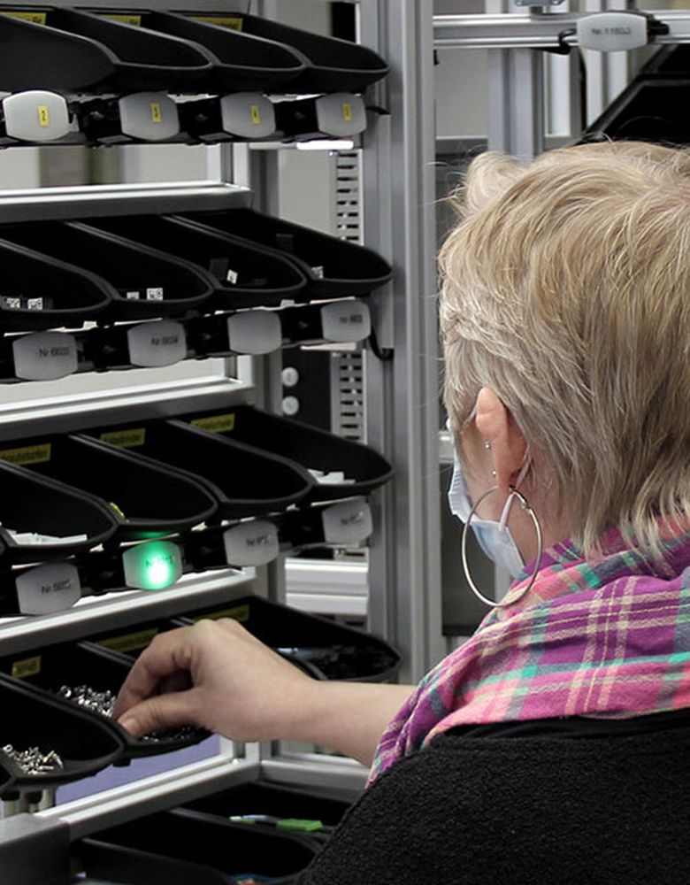Employee picks a component out of a container