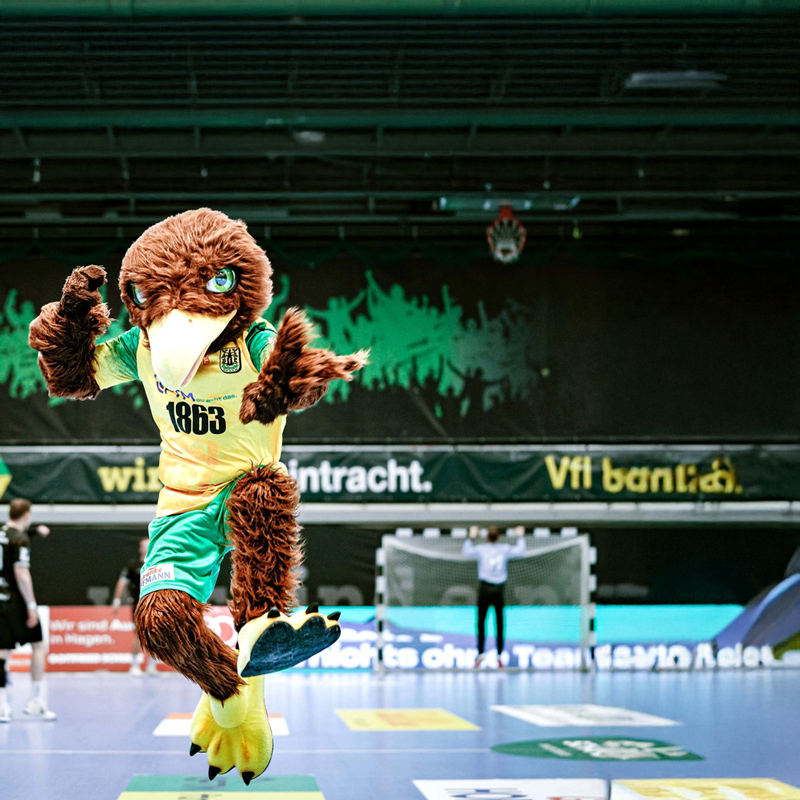 Maskottchen des VfL Eintracht Hagen springt während eines Handballspiels in die Luft