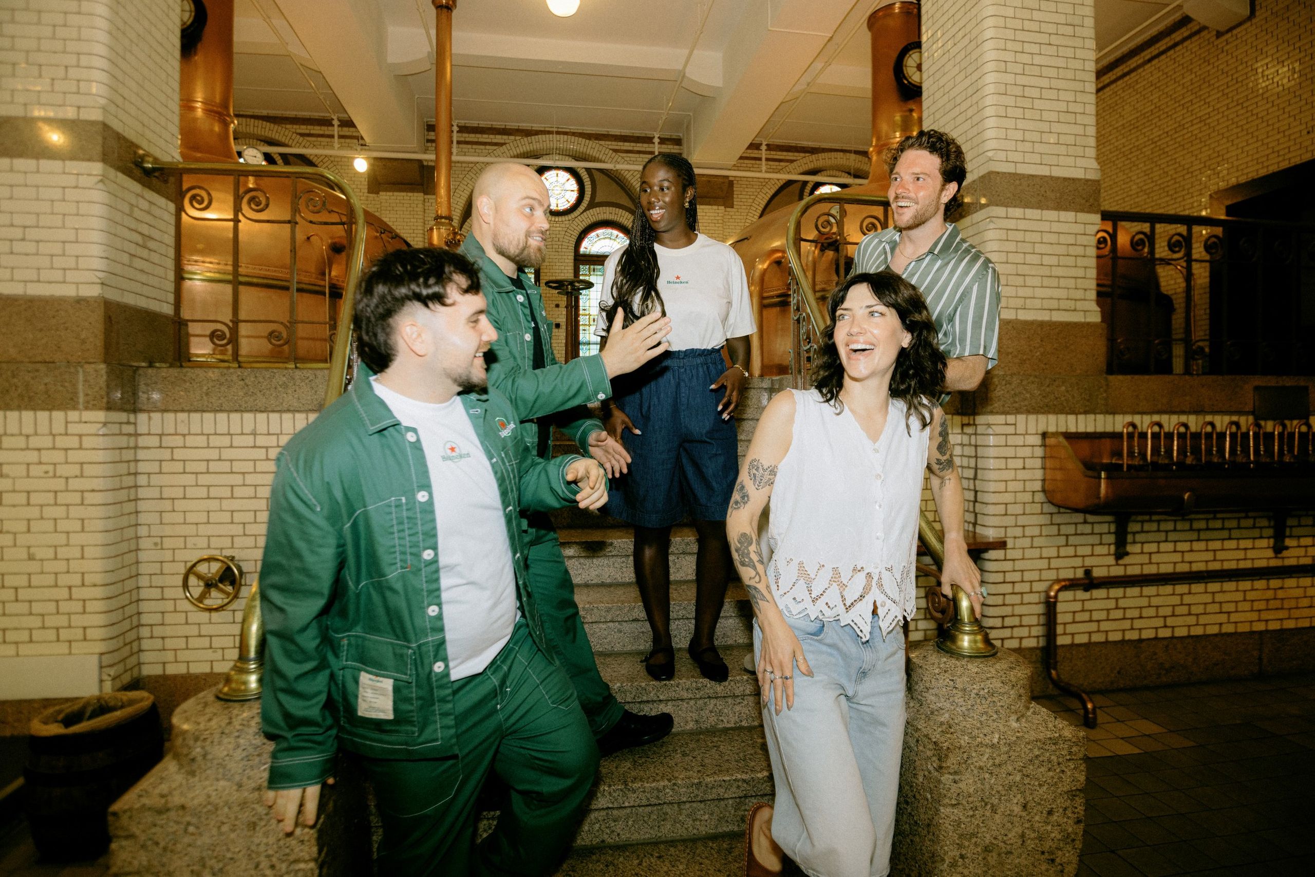 A group of visitors is greeted by the hosts in the brew room of the Heineken Experience