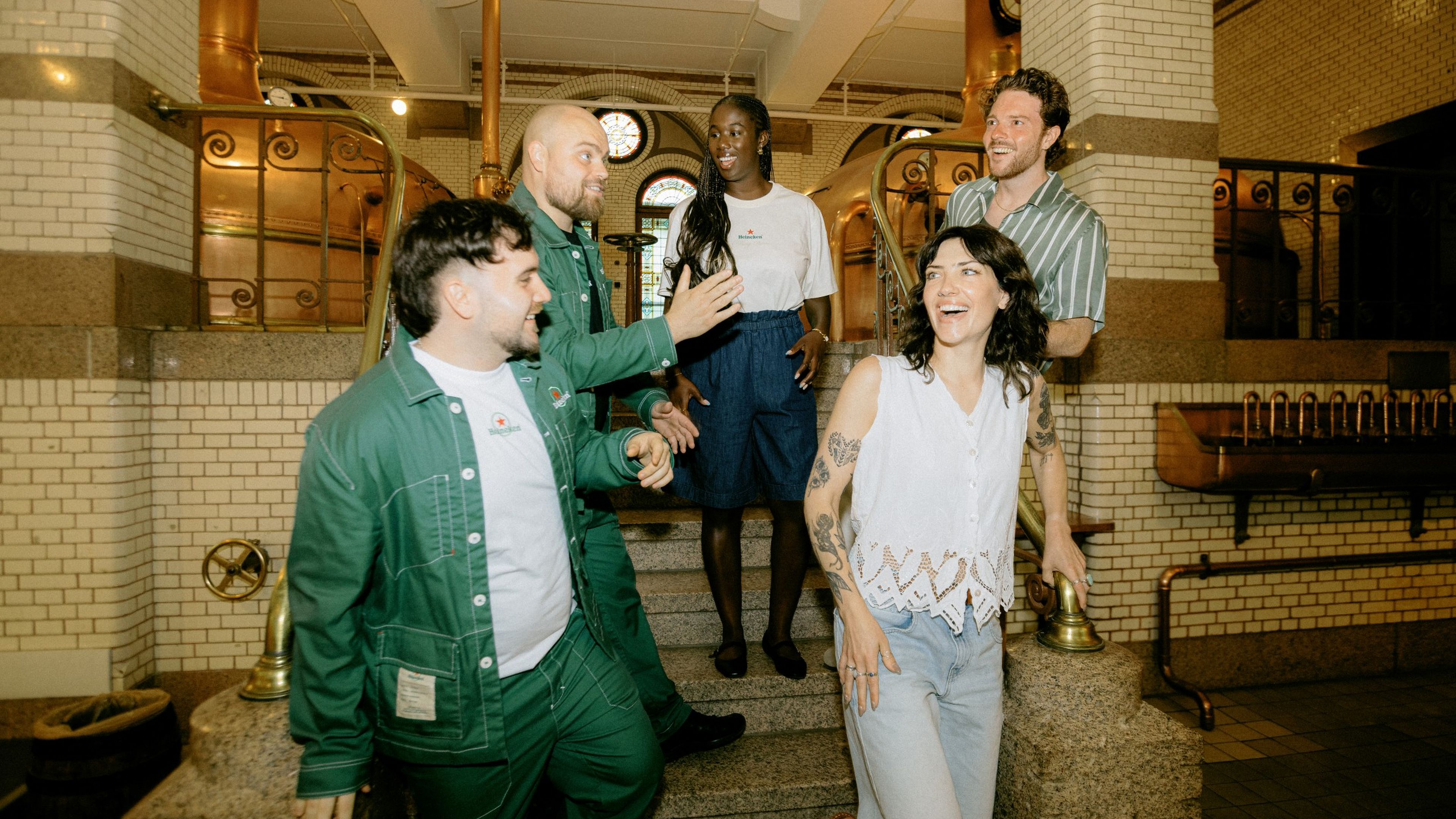 A group of visitors is greeted by the hosts in the brew room of the Heineken Experience