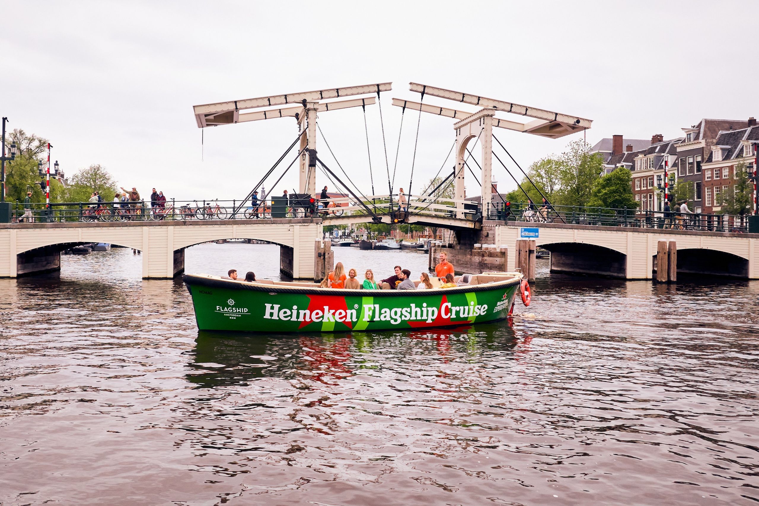 A Heineken flagship cruise boat with passengers enjoying a scenic view in Amsterdam.