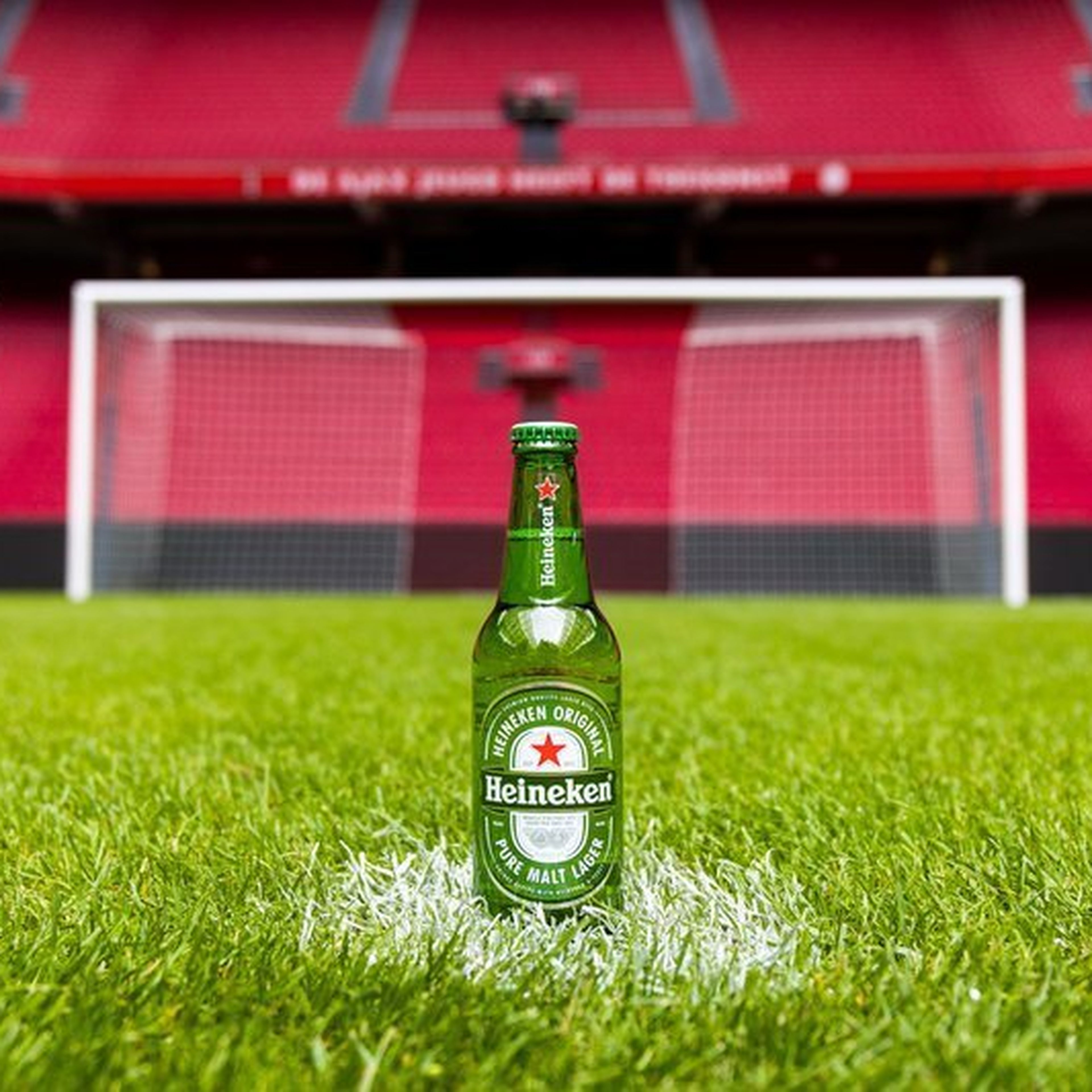 A Heineken bottle on a soccer field with goal posts in the background